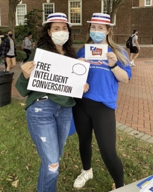 two people wearing patriotic hats holidng a sign saying Free intelligent conversation