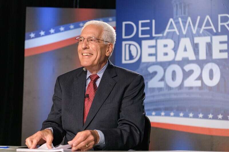 man sitting in front of debate logo